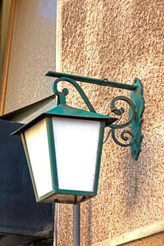 Retro glass lantern with metal frame hanging outside on building facade in city street