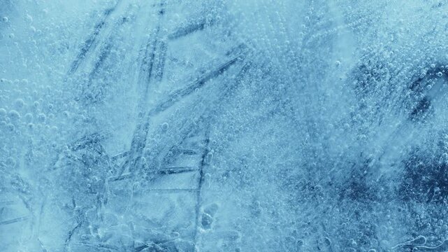 Extreme macro close-up of cracked blue melting ice texture in time lapse. Abstract frozen water surface with translucent crystal patterns, condensation and thawing details in studio lighting.