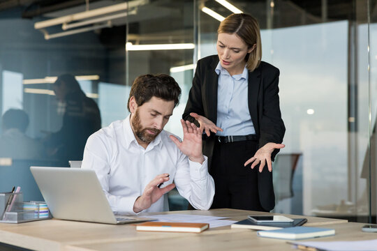 Stressed employee rejecting an argument with his angry female boss during a difficult conversation about workplace pressure and harassment in a modern office setup