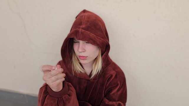 A sad teenage girl holds a bag of white powdered drugs. Stress and depression in children and drug addiction.