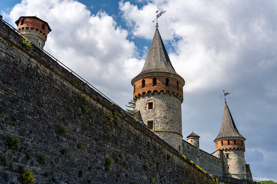 View of Kamianets-Podilskyi Castle with its massive stone walls and pointed towers under a blue sky with white clouds in Kamianets-Podilskyi, Khmelnytska Oblast, Ukraine.