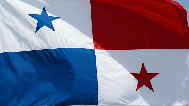 The flag of Panama is shown prominently waving against a clear blue sky. It features a quadrant design with alternating blue and red panels and two stars, one blue and one red, symbolizing the