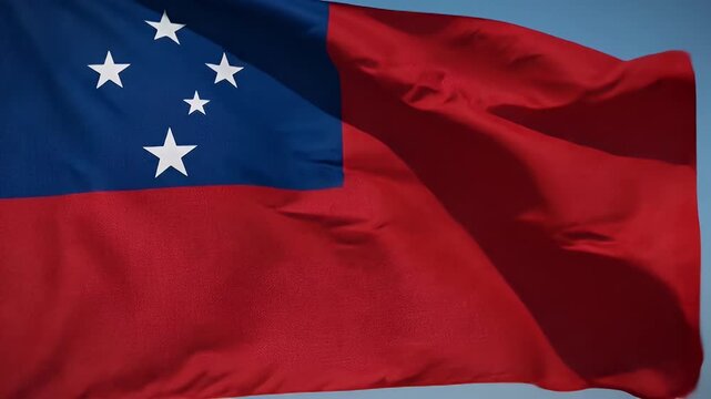 The video captures the flag of Samoa as it waves in the breeze. The flag features a red field with a blue rectangle in the upper left corner adorned with the Southern Cross constellation of stars in