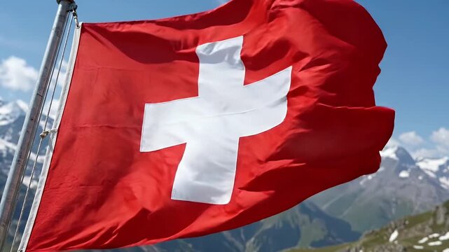 A vibrant Swiss flag waves against the backdrop of a beautiful mountainous landscape. The bright red flag with its distinct white cross symbolizes Switzerland, set against a clear blue sky and
