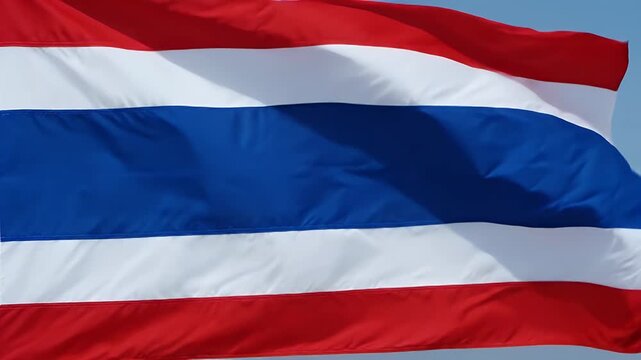 The video displays the national flag of Thailand gracefully waving in the wind. The flag features five horizontal stripes in red, white, and blue colors, symbolizing the nation's unity and pride.