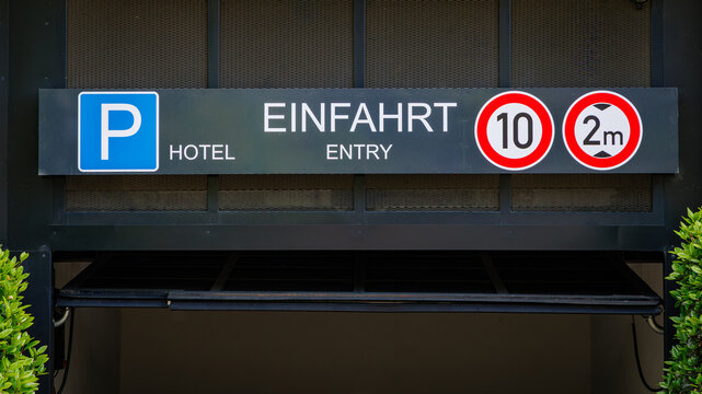 Hotel entry sign with parking information and height restrictions located outside a building in a city setting