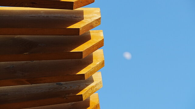 Abstract wooden architecture detail with blurred moon in blue sky