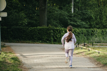 Obraz premium A full-length portrait of a girl running from behind in a park.