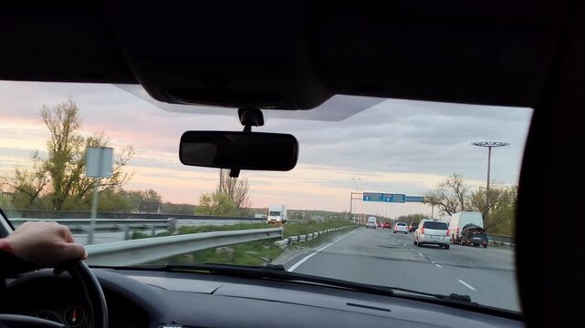 View through the windshield of a car driving on a highway at sunset.