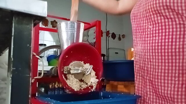 An unrecognizable person is grinding corn flour in a mill to make achira biscuits inside a kitchen in Yaguara, Huila, Colombia. Concept of handmade and small business