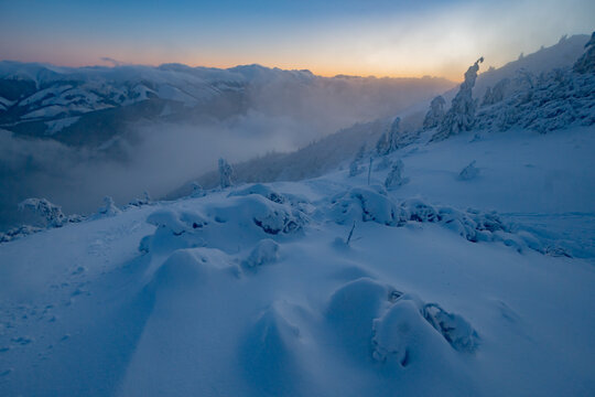 View of Salatin mountain peak covered in deep snow with misty valleys and soft sunrise light over the Low Tatras Liptovska Stiavnica, Zilinsky kraj, Slovakia.