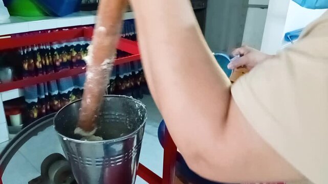 An unrecognizable person places corn flour in a small bowl inside a traditional mill to produce achira biscuits in a kitchen in Yaguara, Huila, Colombia. Concept of handmade and Colombian food