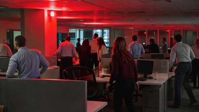 Group of Office Employees Evacuating Workspace During Emergency Alarm with Flashing Red Lights