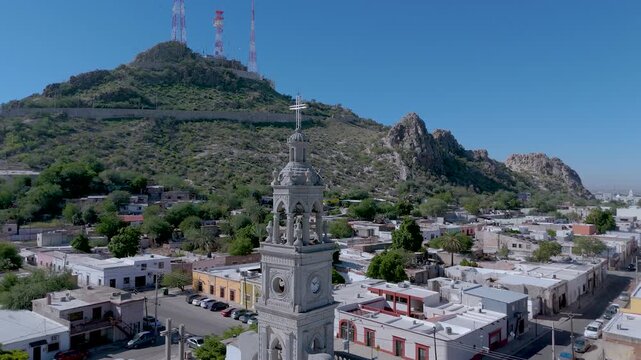 The ornate white bell tower of the Nuestra Se&ntilde;ora del Carmen Parish Church in Hermosillo, Sonora (Mexico). In the background, the iconic Cerro de la Campana rises, its communication antennas visible.