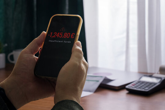 Man checking smartphone showing insufficient funds warning in banking app
