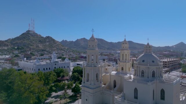 The Metropolitan Cathedral of Hermosillo, Sonora (Cathedral of the Assumption), with its neoclassical and Baroque towers and central dome. The surrounding plaza, with lush trees and a bandstand.