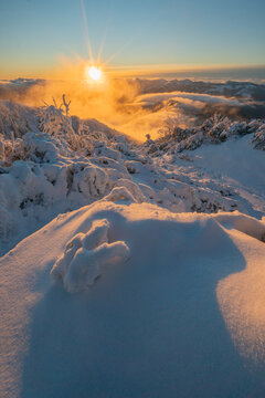 View of the snow-covered slopes of Salatin mountain during a golden sunset with mist in the valley near Liptovska Stiavnica, Zilinsky kraj, Slovakia.