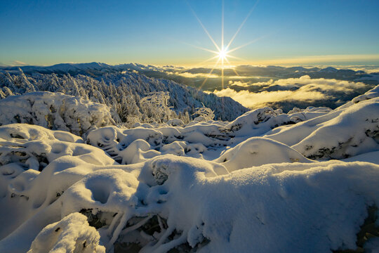 View of Salatin mountain peak with snow-covered trees and a bright sun star over the valley in Liptovska Stiavnica, Zilinsky kraj, Slovakia.
