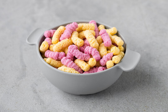 Corn rice fruit and berry ready-made breakfast in the shape of snakes. In a bowl. Close-up. Light grey background