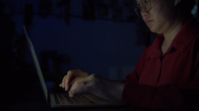 A woman typing on a laptop late at night in the office, capturing fatigue, work pressure, and the atmosphere of staying up to finish an unfinished project.