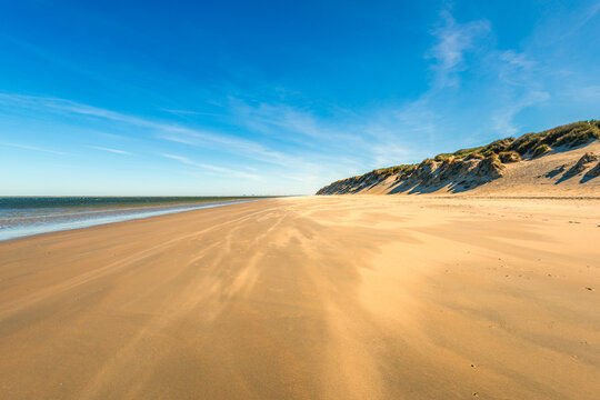 Overview of a Dutch sandy beach at low tide. The photo was taken on a sunny spring morning on the North Sea coast of the former island of Goeree-Overflakke, South Holland province.