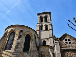 Fototapeta premium Low angle view of the historic Saint-Pierre de Montmartre church, one of the oldest surviving churches in Paris. The image showcases the Romanesque architecture, including the square bell tower, round