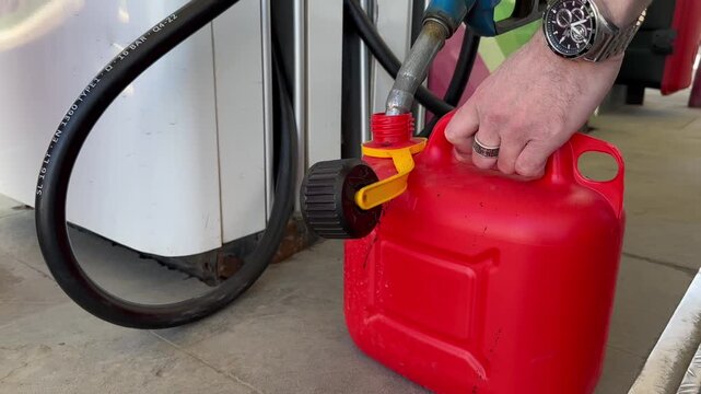 Video of filling a canister with gasoline at a gas station. Filling gas can with gasoline. Refueling pump nozzle and red fuel container at petrol filling station.