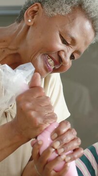 Vertical video: Holding piping bag, senior guiding child in kitchen piping pink icing onto cupcakes