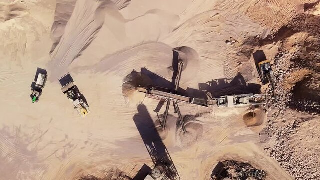 Aerial drone view of active quarry processing with excavator feeding stone into crushing and screening plant while wheel loader loads aggregate into dump truck. Industrial mining machinery sorting