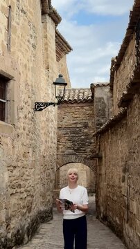 Female traveler checking a city map while exploring the historic streets of Baeza, Spain. Vertical travel video with authentic European architecture, cultural tourism.