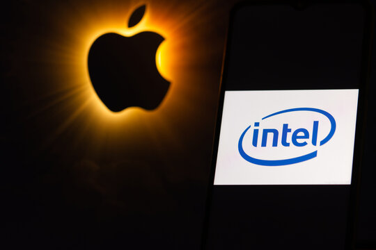 The Intel logo is displayed on a mobile phone, with the Apple logo shown in the background, illustrating the concept of using Intel AI chips in Apple devices such as iPhones and computers in New York,