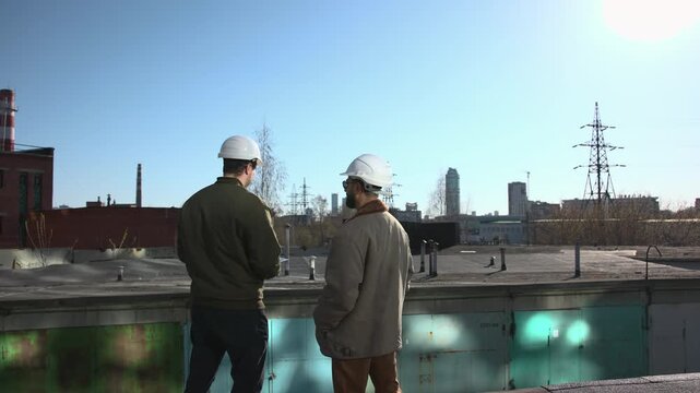 Two Experts Diligently Examine Parapets And Towers Against Industrial Backdrop With Professionalism. Media