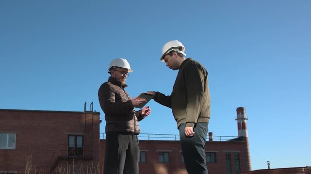 Two Professionals Exchange Documents On Rooftop During Formal Handover And Site Approval Meeting. Media