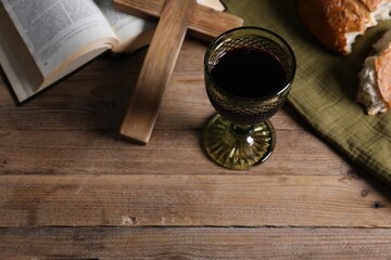 Obraz premium Holy Communion. Wine in cup, bread and Bible on wooden table, above view. Space for text