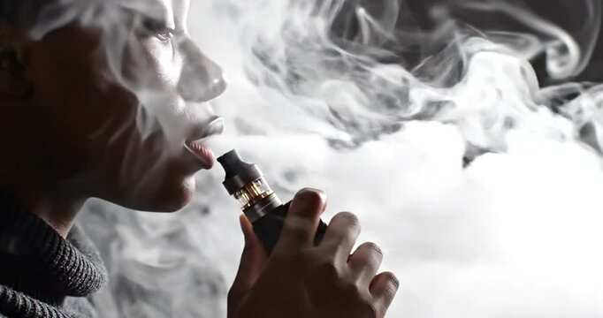 Person exhaling vapor cloud using electronic cigarette or vape pen with modern lifestyle concept