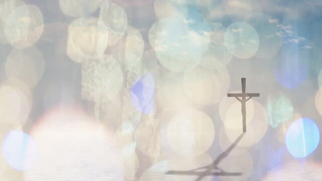 Crucifix standing while bokeh lights shifting, shadow casting down-left, revealing sky and water