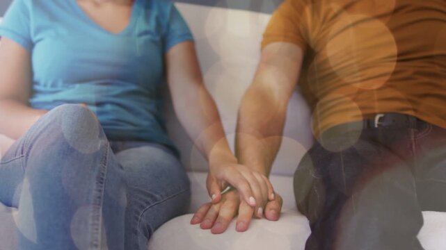 Couple reaching hands on white sofa, linking fingers, showing affection, lifestyle bokeh sweeping