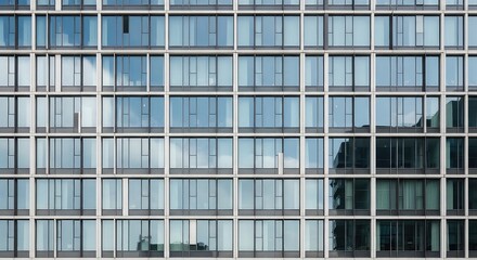 Obraz premium Modern building facade with repeating glass windows reflecting sky