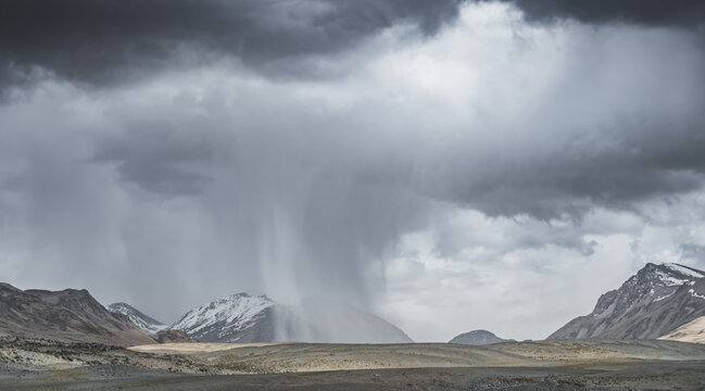 Mountain landscape, rocky peaks and ridges with snow and glaciers, a panorama in the mountains. Tien Shan in the Pamirs, desert terrain and cloudy weather with rain in the high mountains
