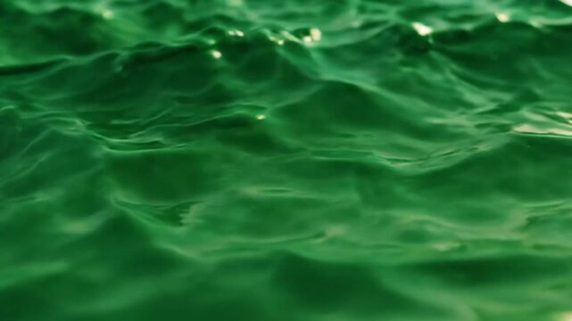 Close-up of shimmering emerald green water creating gentle ripples and waves.
