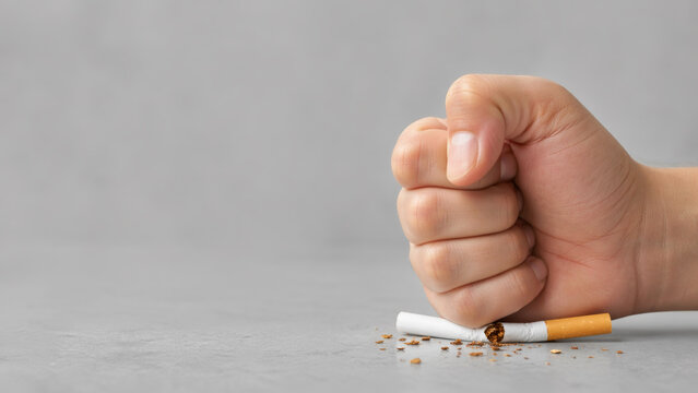 Concept of quitting smoking with a hand smashing a cigarette, representing willpower and healthy lifestyle.