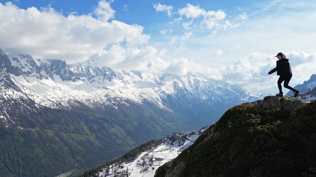 Young woman celebrating on a mountain summit above the Chamonix valley in the French Alps, filmed in cinematic slow motion