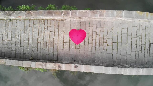 Aerial overhead view of Devils Bridge, Lucca. Red heart shape umbrella on the bridge