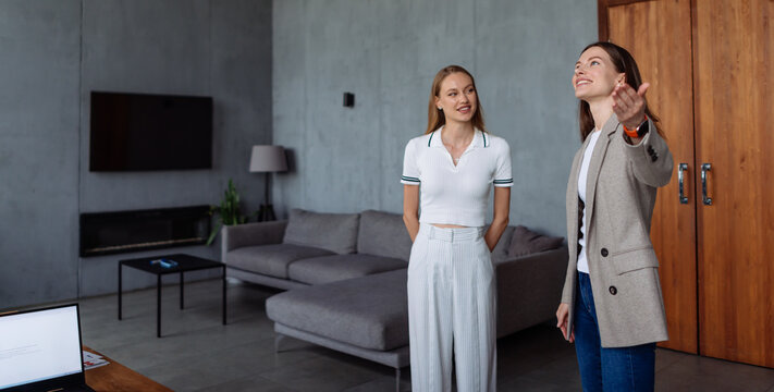 Real estate agent discussing and presenting a contemporary living room interior with a potential buyer, highlighting features and space in a new home property