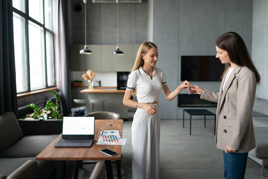 Real estate agent hands keys to smiling female client in a modern urban apartment, celebrating successful purchase or rental and the start of new ownership and contemporary city living