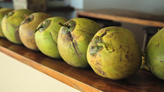 Close shot of fresh buko coconuts arranged on wooden table in tropical setting