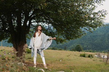 Naklejka premium Casual lifestyle portrait of a woman standing in a grassy field with trees in the background, relaxed pose, soft natural light, open landscape, serene outdoor mood