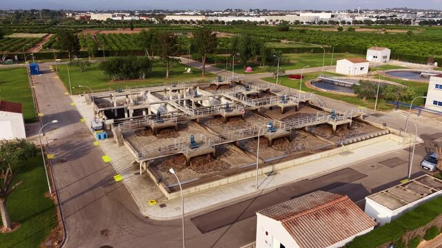 Aerial view of bioreactor aeration basins at a municipal wastewater treatment plant showing activated sludge process, mechanical surface aerators, concrete tanks, and secondary clarifier