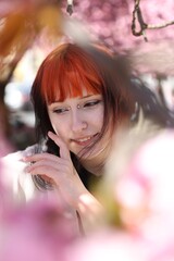 Naklejka premium Beautiful young girl posing near blossoming sakura tree outdoors