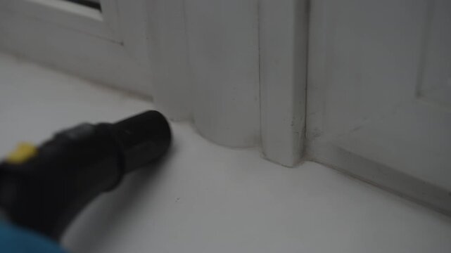 Household steam cleaner effectively removing dirt and grime from white plastic window frame, followed by hand wiping surface with pink microfiber cloth for spotless result. Shooting in slow motion.